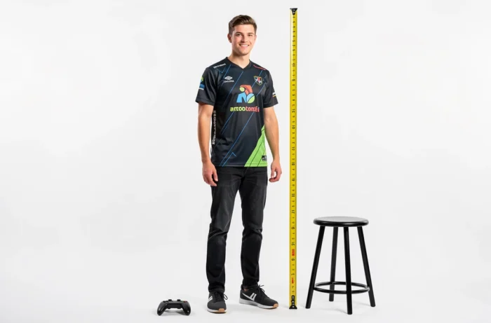 Portrait en pied d'un grand streamer français en jersey esport, illustrant sa taille dans un studio photo épuré